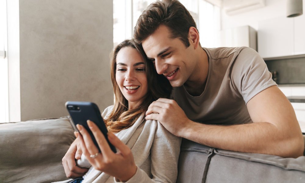 casal jovem com o celular em mãos para usar o simulador de financiamento