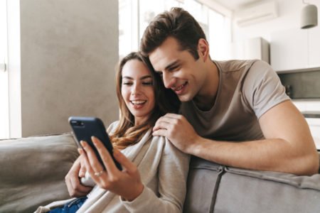 casal jovem com o celular em mãos para usar o simulador de financiamento