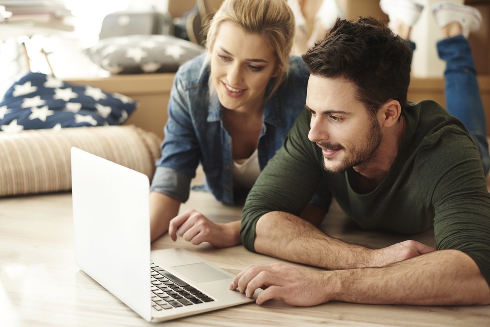 casal jovem procura imóveis no notebook 