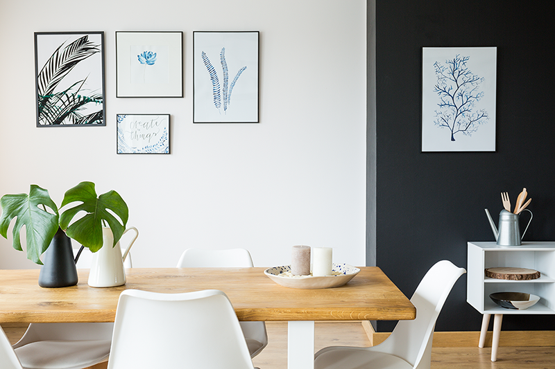 parede da sala de jantar em preto e branco com uso de quadros e ilustrações