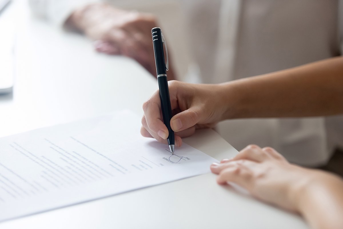 mãos femininas assinando contrato de compra