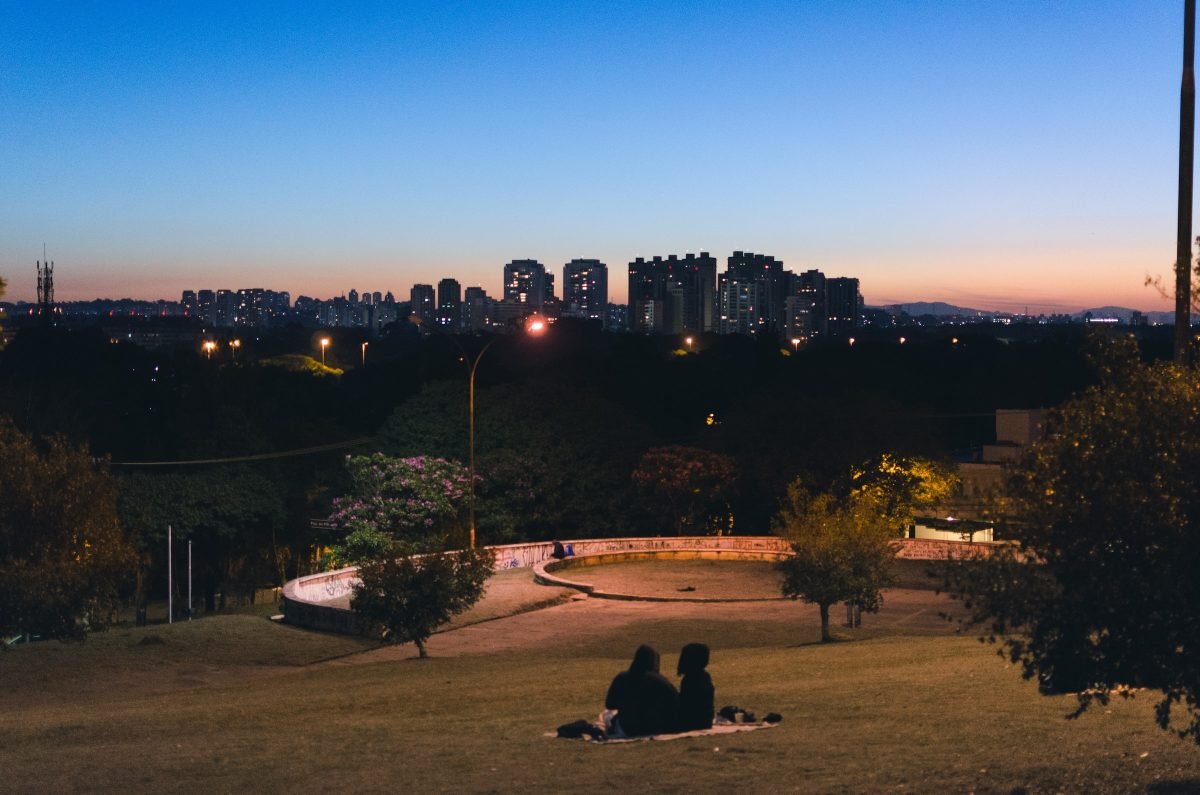 Casal sentado na grama observando a vista da Praça do Pôr do Sol