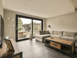 uma sala de estar com um sofá, mesa de centro e porta de vidro deslizante que se abre para o pátio do quintal