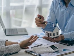 Conceito de compra de casa, corretor imobiliário com modelo de casa conversando com o cliente sobre a compra de seguro residencial e o cliente assinando contrato sob acordo formal com direito imobiliário